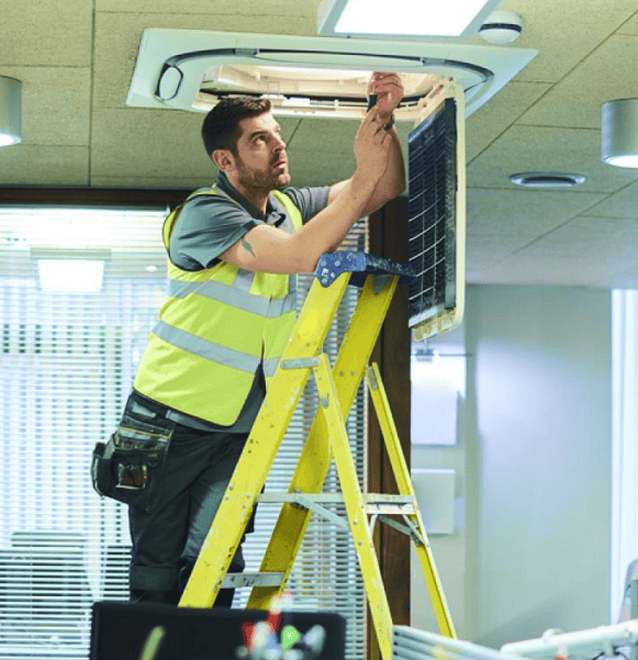 Technician installing security system in ceiling with ladder.