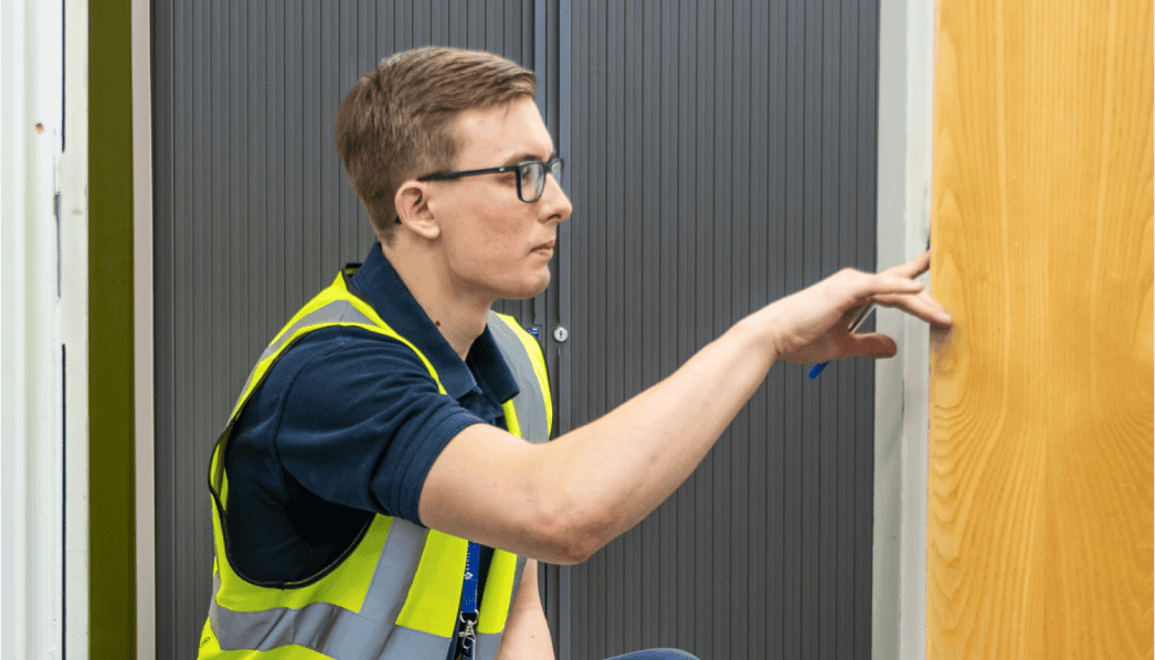 Person inspecting fire door for safety and regulation compliance.
