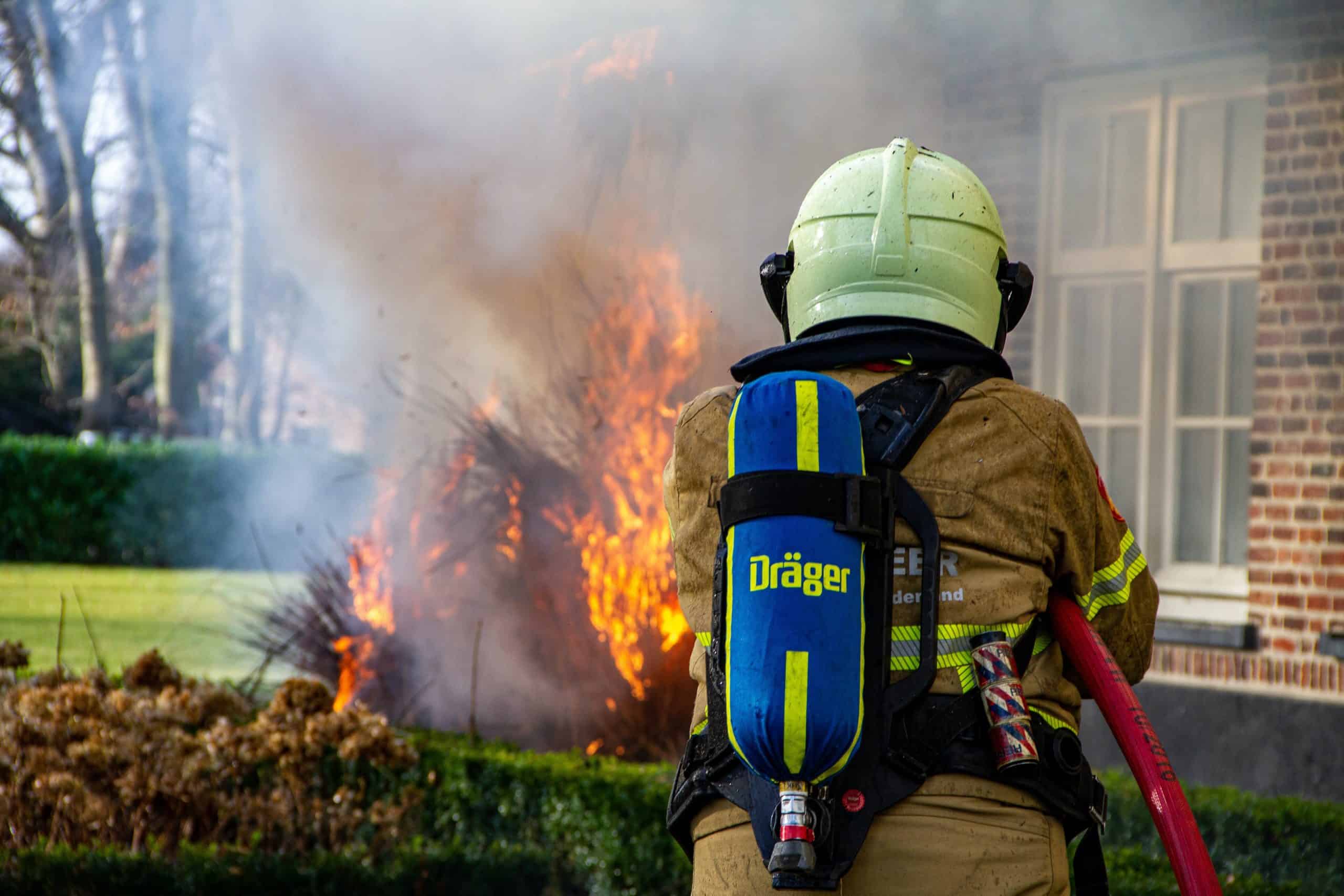 Firefighter with Octagon-shaped fire safety gear in front of house fire.