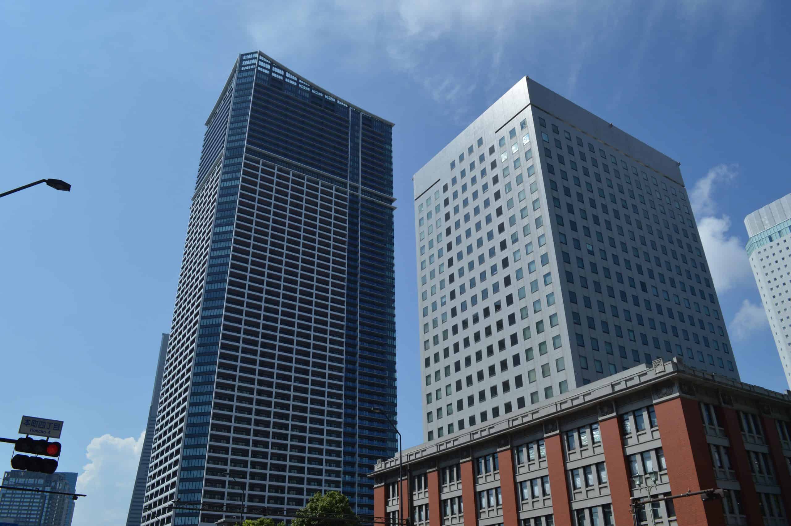 Tall modern office buildings in a city skyline under blue sky.